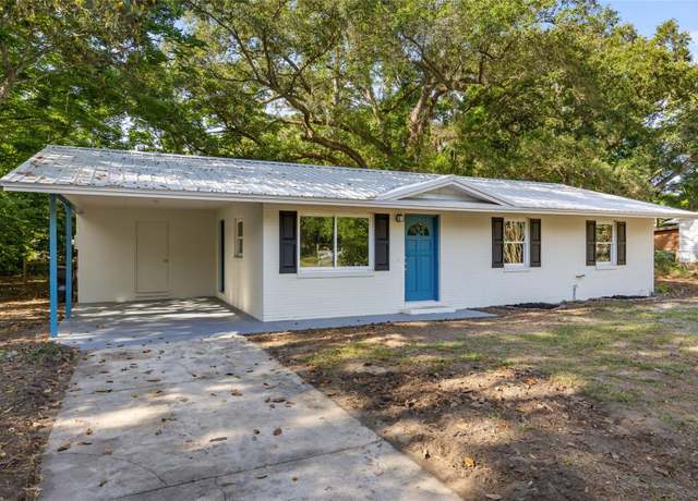 White single-story home with blue accents in Alachua, Florida